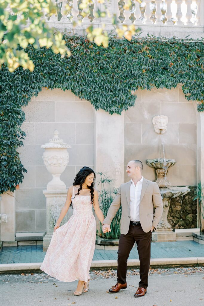 Andrea and Rich during their fall Longwood Gardens engagement, walking hand in hand through vibrant autumn foliage.