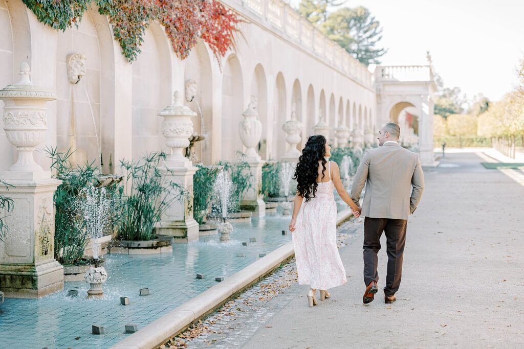 The Italian fountain garden at Longwood gardens walking hand and hand during their engagement photos 
