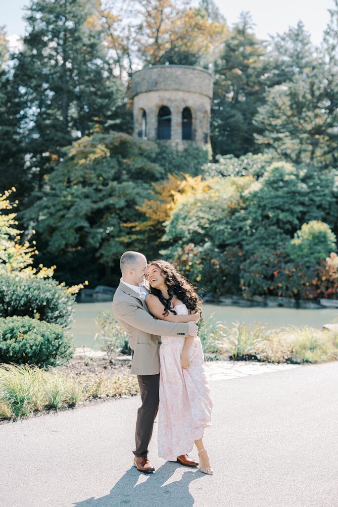 Candid fall Longwood Gardens engagement moment with Andrea and Rich laughing together among the gardens’ colorful leaves.