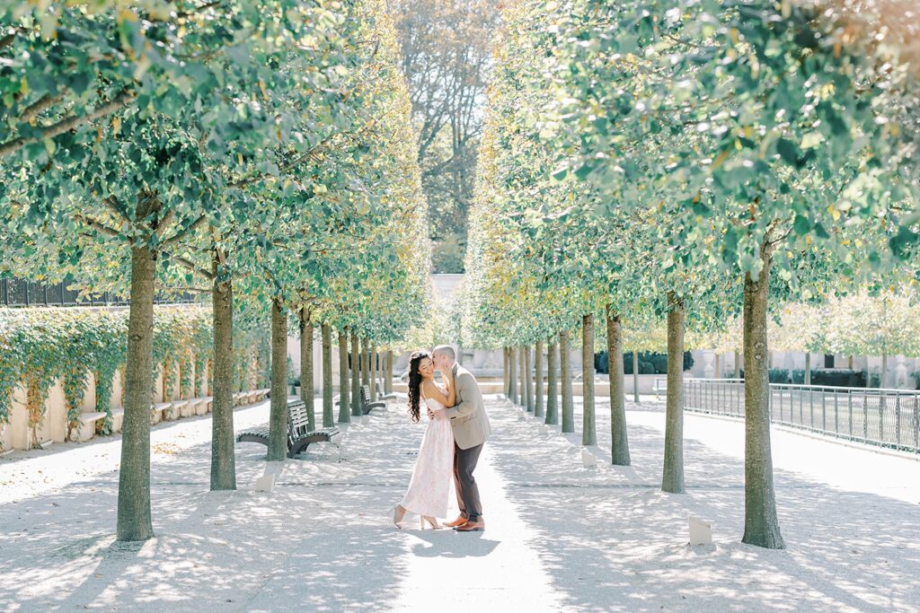 Elegant fall Longwood Gardens engagement portrait of Andrea and Rich framed by golden trees and classic stone architecture.