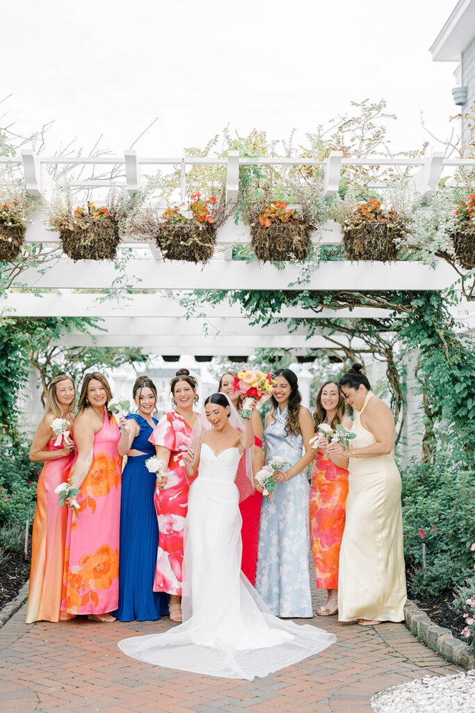 Bride with bridesmaids in vibrant coral and pink dresses at New Jersey wedding