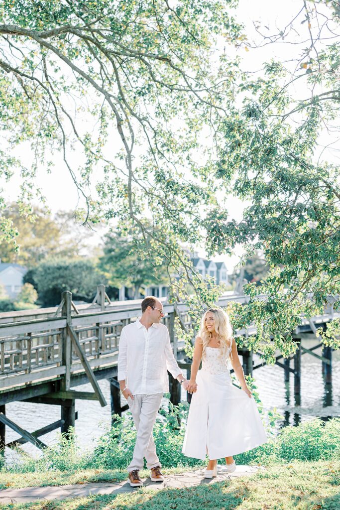 A New Jersey Spring Lake beach engagement couple walking hand in hand on dock