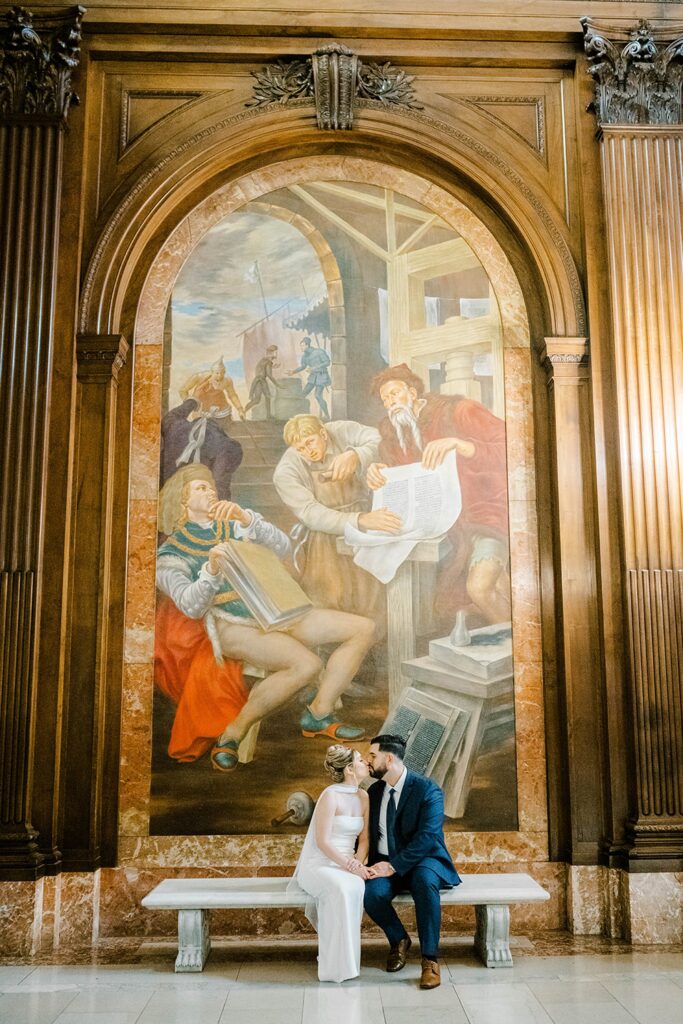 Giovanni gently kisses Stefanie’s forehead beside towering columns at the New York Public Library in Manhattan.