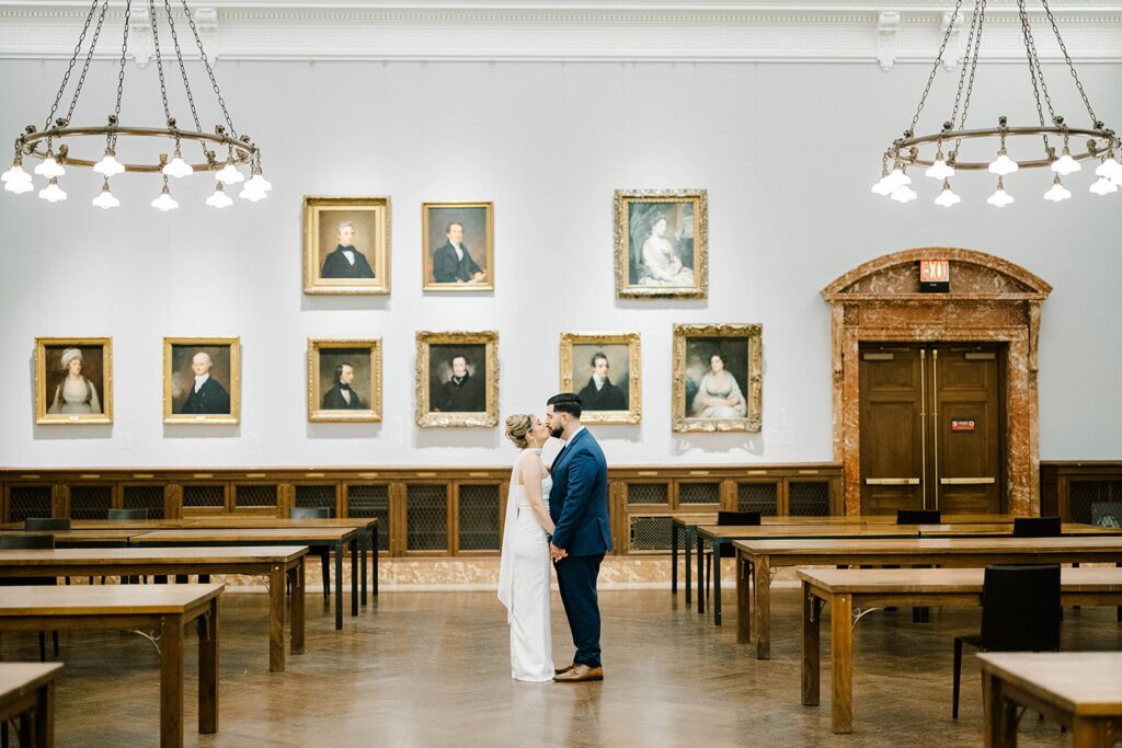 Wide engagement portrait of Stefanie and Giovanni with the New York Public Library’s grand facade and NYC streets in the background.