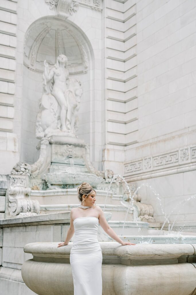 Stefanie in her romantic engagement gown with a timeless updo, framed by the ornate architecture of the New York Public Library.
