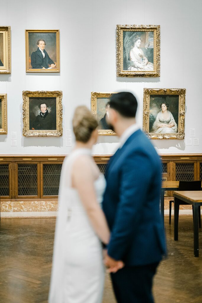Editorial engagement portrait of Stefanie and Giovanni on the iconic New York Public Library steps against classic Beaux-Arts architecture.